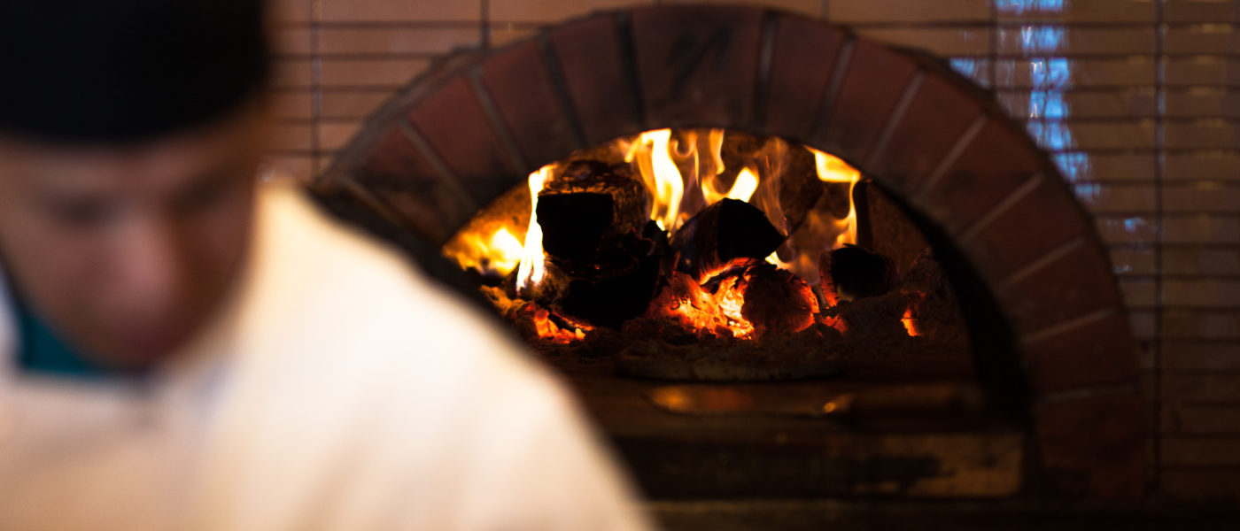 Bentwood Tavern's brick wood fire pizza oven behind a line cook