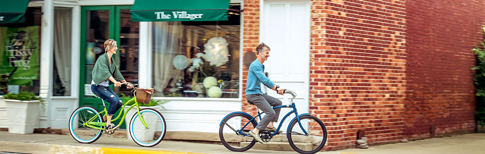 a woman and a man ride cruiser bikes down a New Buffalo downtown sidewalk