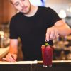 Bentwood Tavern bartender garnishes a summer cocktail with blackberries