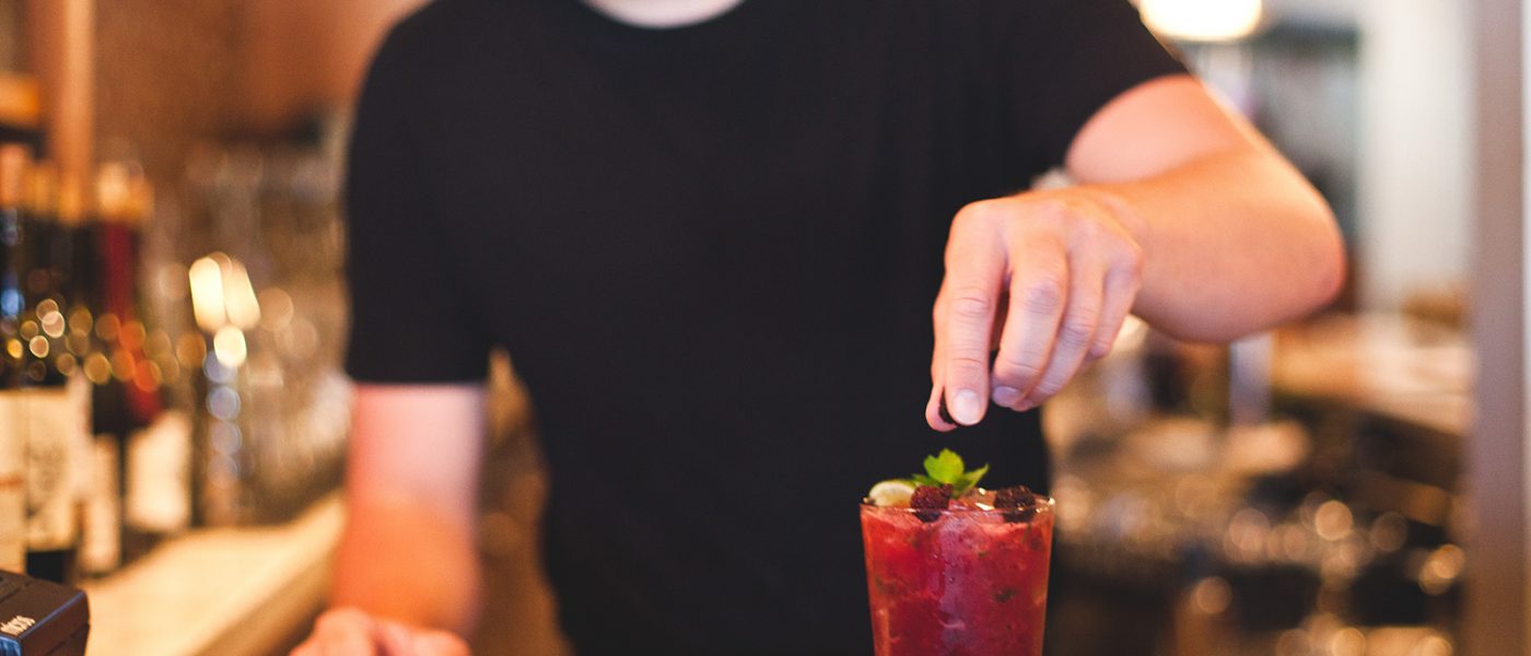 Bentwood Tavern bartender garnishes a summer cocktail with blackberries