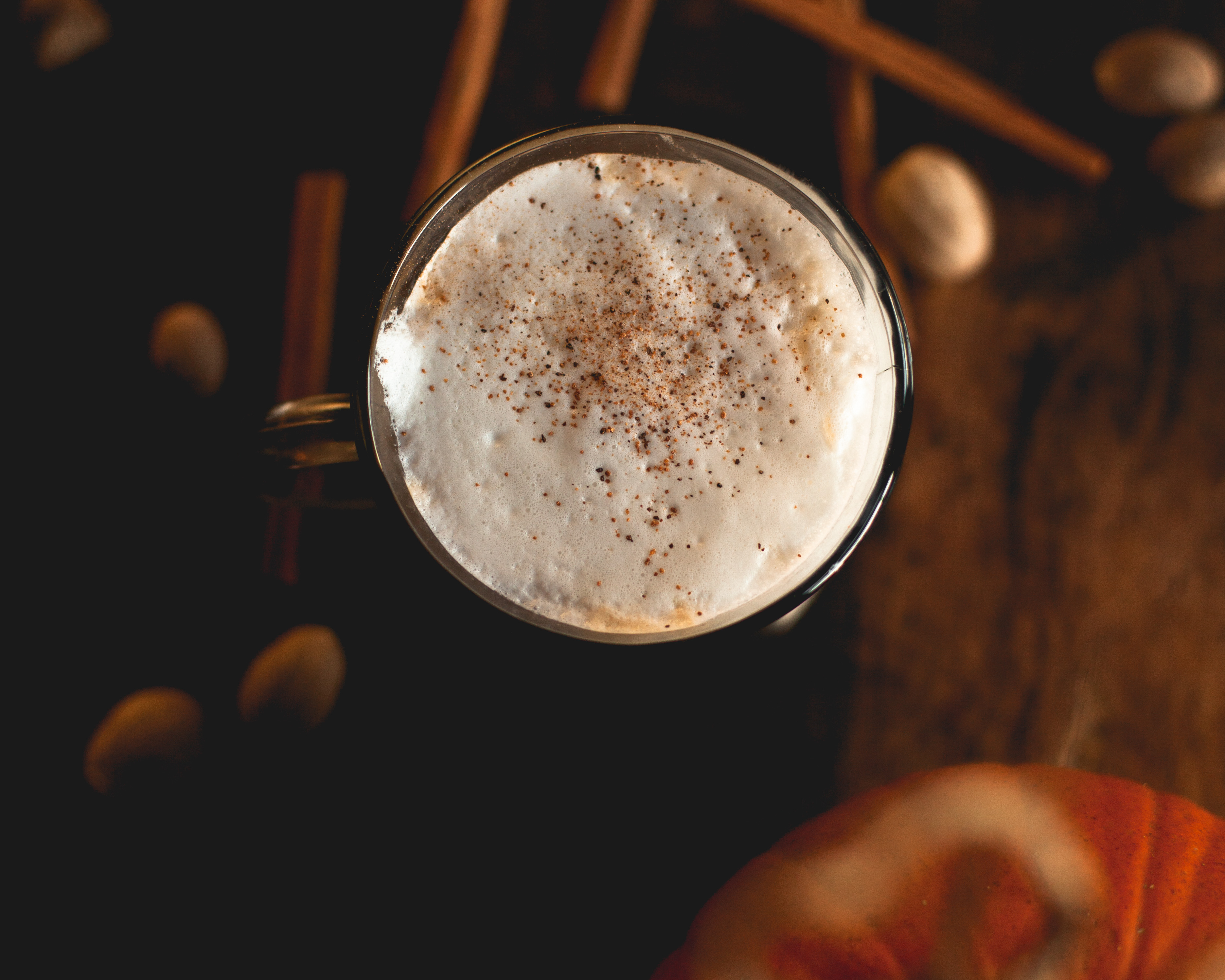 joe_pumpkin-spice-latte foamy latte with cinnamon on top and surrounded by pumpkin, cinnamon & nutmeg