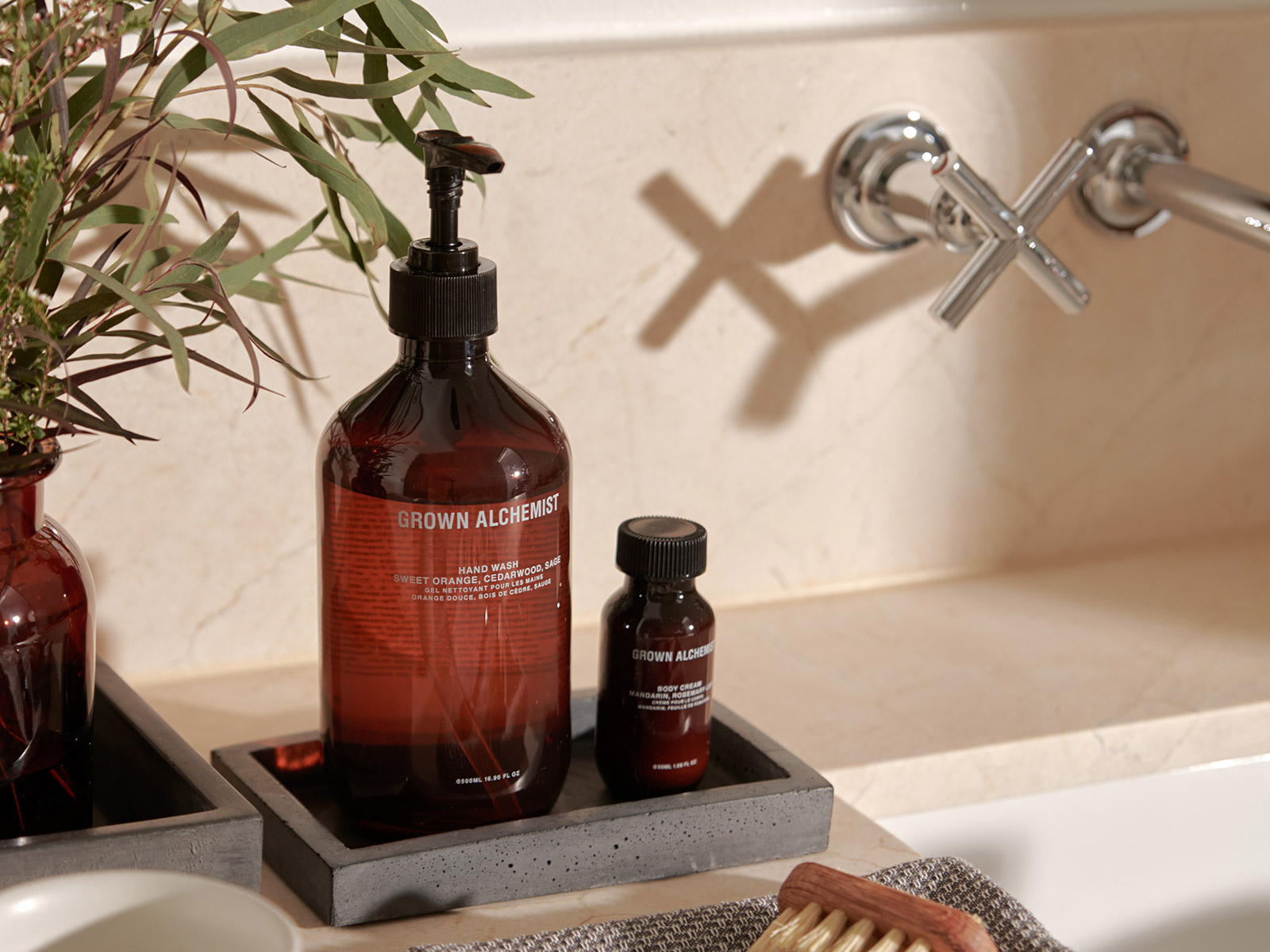 Sink with Grown Alchemist handsoap and lotion with eucalyptus in the background.