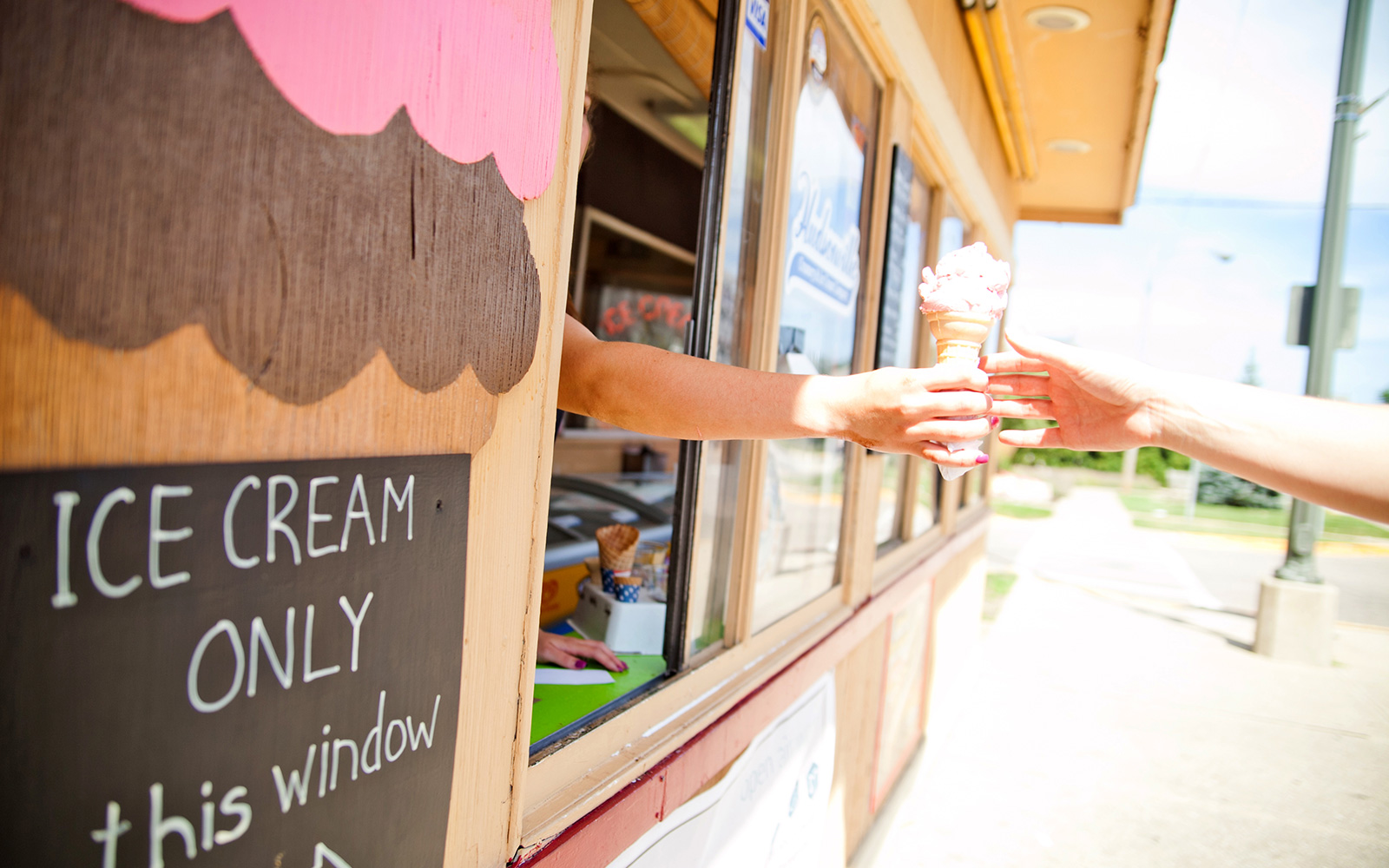 ice cream is handed out through a window to a customer