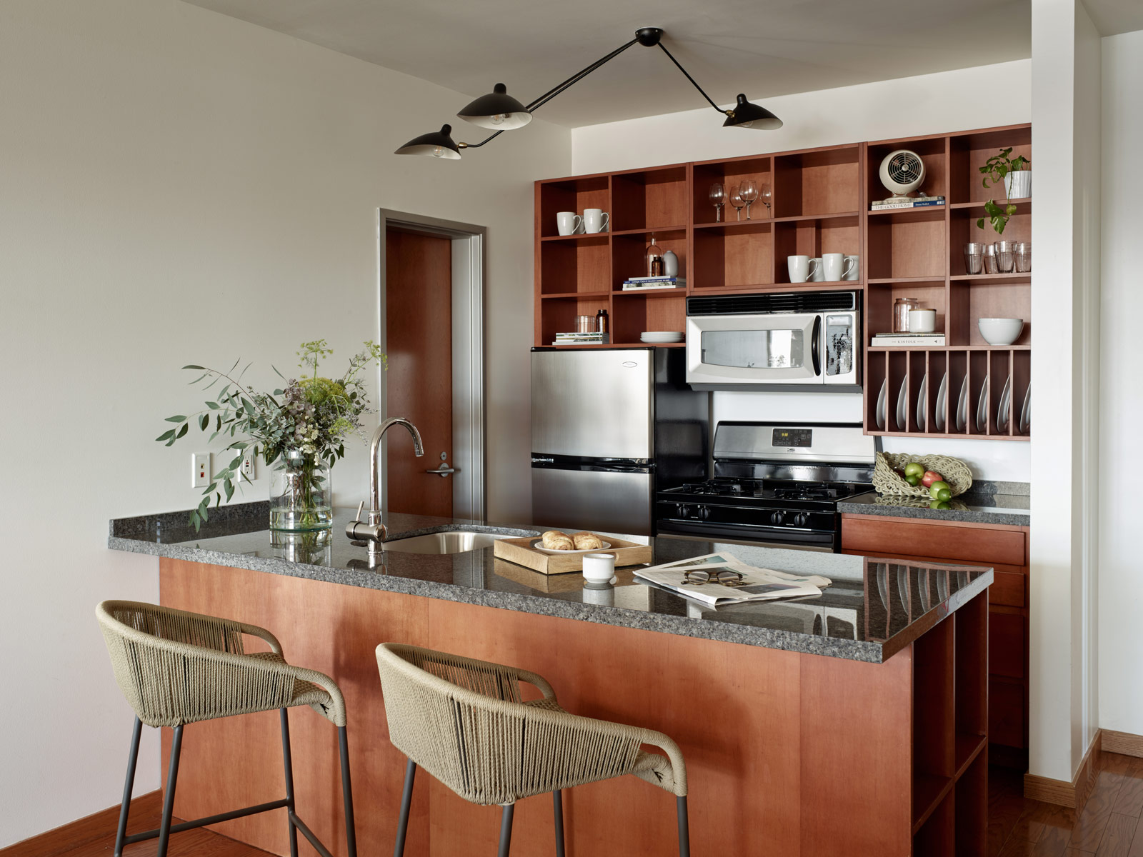 Kitchen with wood cabinets, two barstools and modern light fixture at Marina Grand Resort in New Buffalo, Michigan.