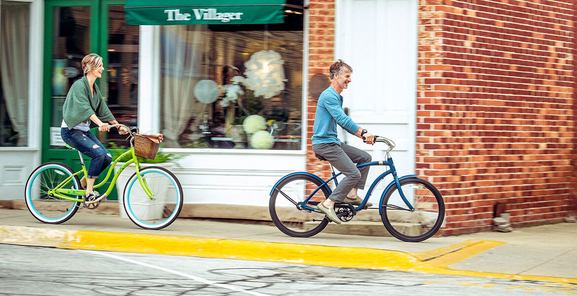 a woman and a man ride cruiser bikes down a New Buffalo downtown sidewalk