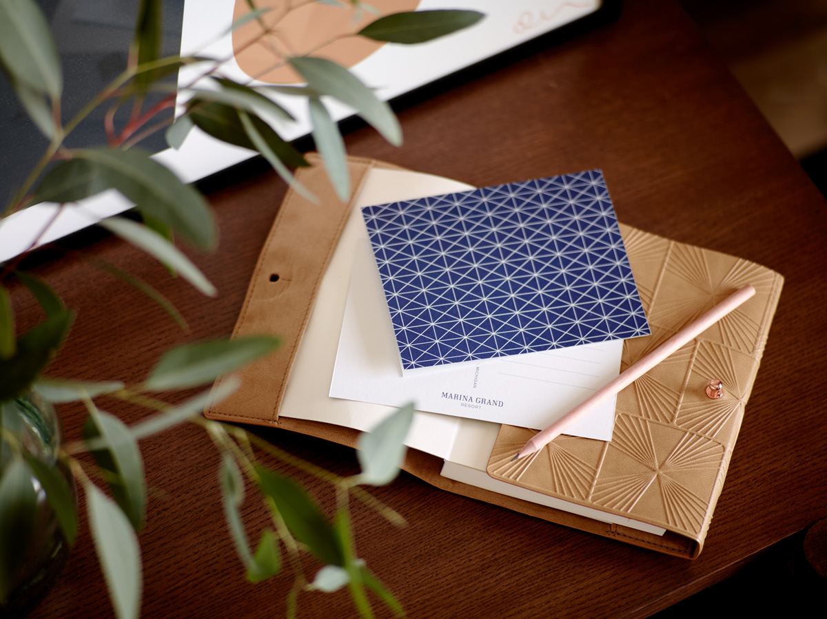Notecard with blue pattern, pencil and leather notebook with eucalyptus.