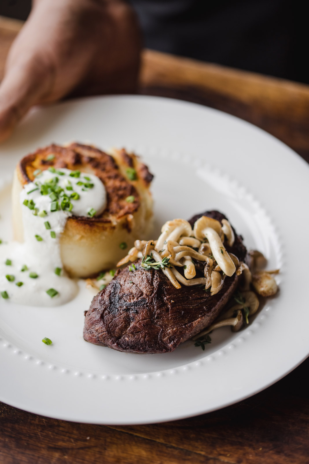 kobe-steak white plate with kobe steak topped with mushrooms and golden-brown potato stack on the side