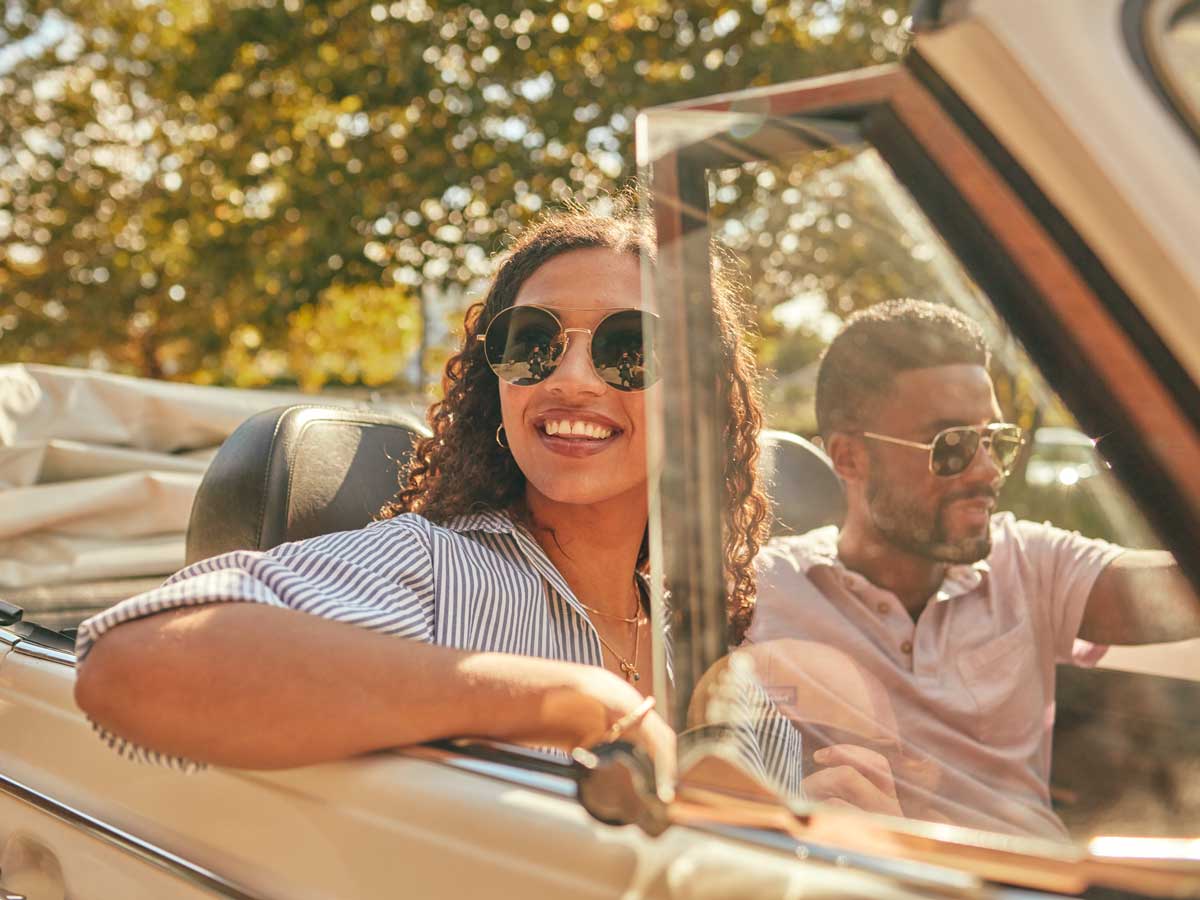 Summer time in New Buffalo A woman and a man in a convertible smiling and driving
